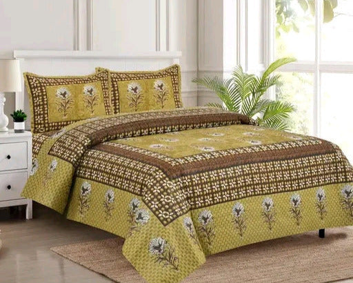 Green and brown floral patterned bedspread on a bed in a bright bedroom.
